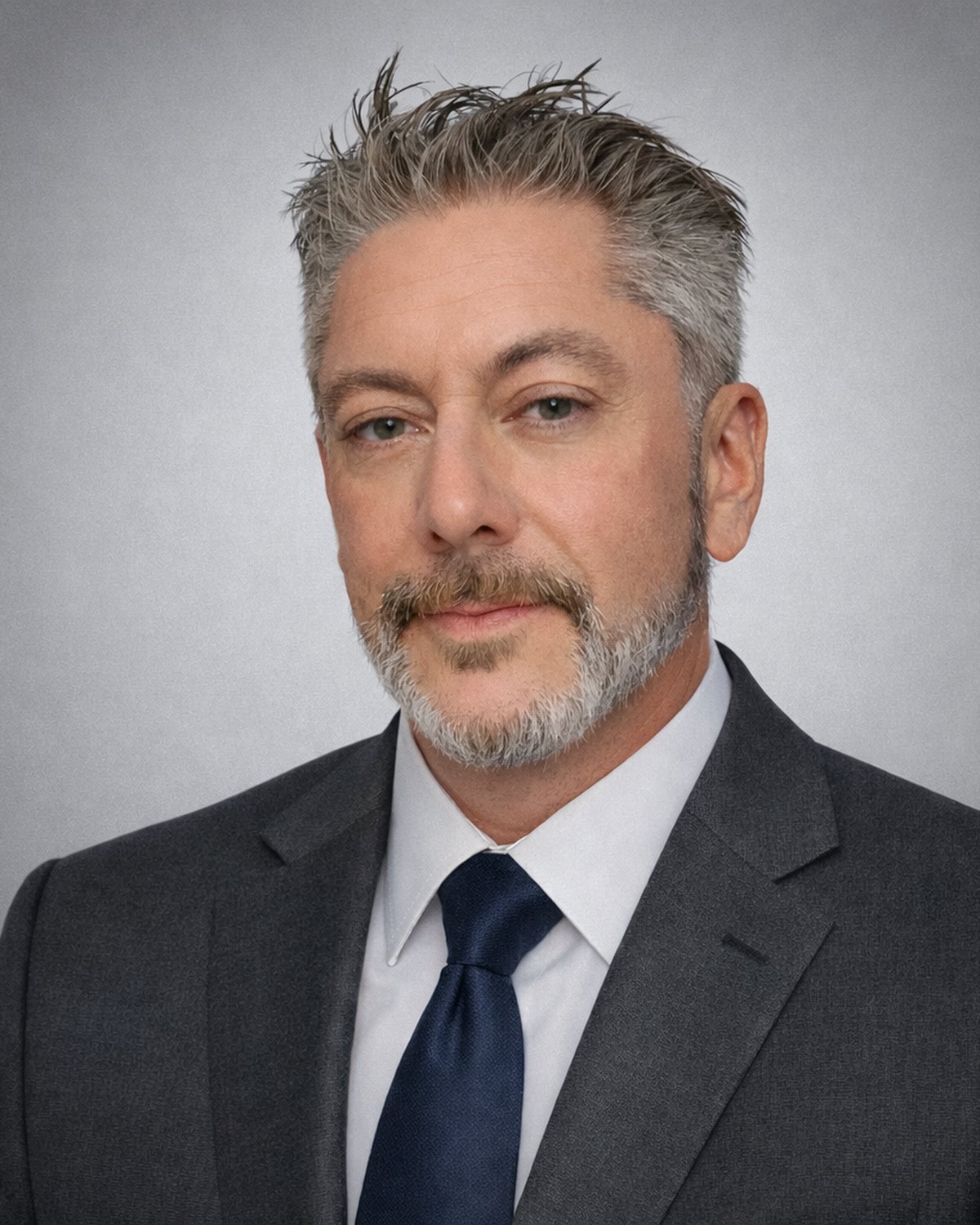 James Allen Heifner, photographed in a dark suit against a grey studio background.